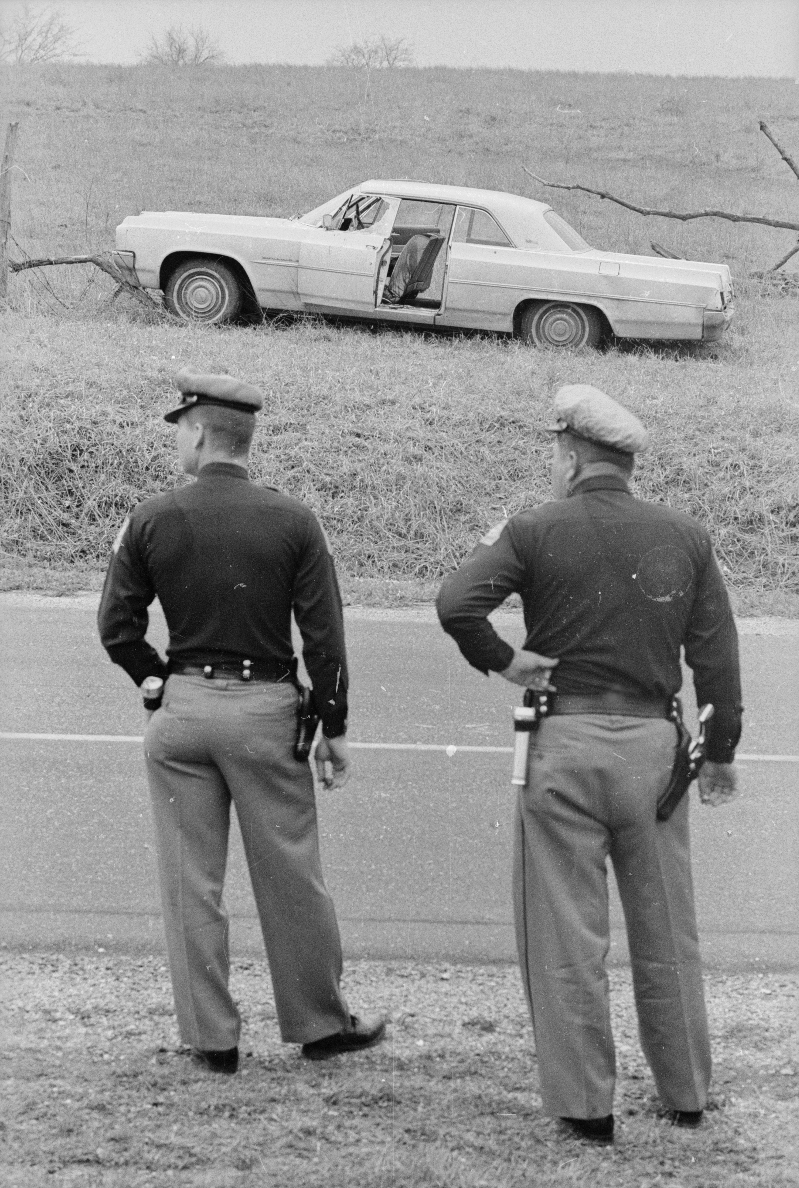 April 1, 1965:  Two Alabama state troopers standing over the road from the wreck of the car belonging to the murdered Detroit housewife, Viola Liuzzo, who was killed by a group of Ku Klux Klansmen after having taken part in a civil rights march from Selma to Montgomery.  (Photo by William Lovelace/Express/Getty Images)